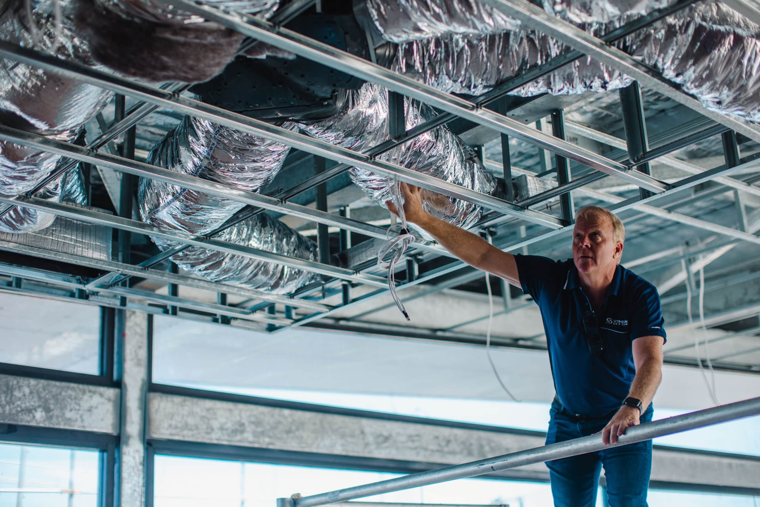 Brad Stinson checking reverse cycle air conditioning ducting in Perth warehouse